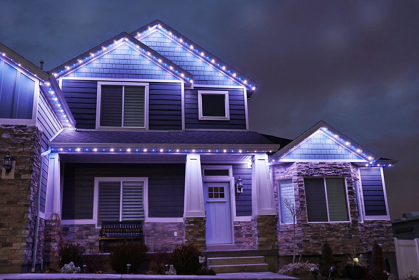 Blue and white permanent lights on gables and the porch roofline